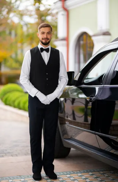 Chofer profesional con uniforme formal y guantes blancos junto a un auto negro, representando la elegancia y discreción de Yo Te Salvo.