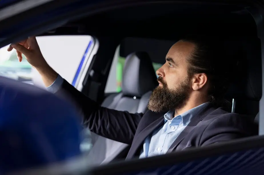 Un hombre de negocios sonriendo mientras revisa su smartphone en el asiento trasero, ilustrando la ventaja de optimizar el tiempo con Yo Te Salvo.