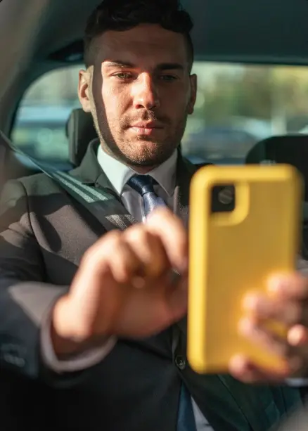 Ejecutivo revisando su smartphone en el asiento trasero, ilustrando la libertad de movimiento con el servicio de chofer por horas.